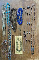 Photo showing multiple beaded necklaces and a set of handmade earrings on a wooden background.