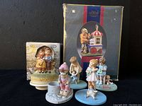 Lot of six porcelain figurines including three Danbury Mint Bessie Pease Putmann votive holders, Melody In Motion musical figurine, and two additional child figurines, shown with original box for musical figurine.