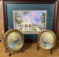 Large framed print with gazebo scene and burgundy mat and black frame, positioned behind two smaller oval framed pictures in gold-toned frames.