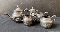 Four piece Hamilton quadruple plate pewter tea service set with teapot, sugar bowl, creamer, waste bowl displayed together on black surface against textured backdrop.