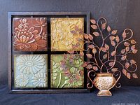 Metal wall decor piece with four floral embossed square panels in a frame with rust and earth tones.