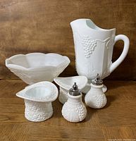 All pieces arranged on wooden surface showing pitcher, footed bowl, shakers and top hats