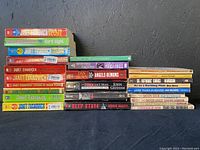 Stack of paperback books by Janet Evanovich, Edgar Rice Burroughs, Stephen King, and John Grisham with visible staining and wear.