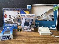 Lot showing two boxed washer-less kitchen faucets, Talking Caller ID LCD Touch Panel Phone in box, and Tic Tracer voltage detector box