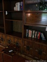 Bookshelf with 24 assorted books arranged on shelves in the background with a wooden cabinet below.