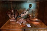 Three bird-themed decorative items on wooden shelf: wooden eagle sculpture, painted bird figurine, wooden duck lamp.