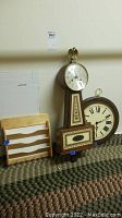 The full lot showing two clocks and one wooden organizer rack side by side on the floor against a wall