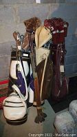 Three sets of golf bags with numerous golf clubs and various headcovers such as knit and leather styles.