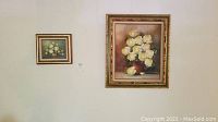 Two framed floral oil paintings hung on a wall, one larger than the other