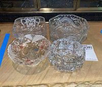 Photo showing top view of four vintage cut glass bowls, displaying intricate pattern details and shapes.