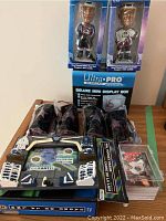 Photo showing two NHL bobbleheads in original packaging, five unopened NHL star sticks, a stack of hockey cards, and a mini display box.