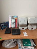 Lot setup showing JBL Control 1 speakers, TI-83 Plus calculator in package, two electronic organizers, and Sanyo CD player on wood surface.