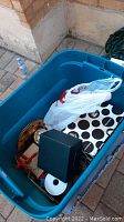 Blue storage bin containing boxed lamps, Christmas themed bags, and assorted ornaments
