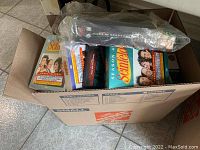 Box top view showing multiple DVD sets and sealed game cases