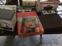 Lot displayed showing empty flatware box, Christmas reindeer platter, flatware sets and other kitchen tools on table.