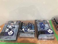 Photo showing all three unopened Toronto Maple Leafs McFarlane NHL figurines in packaging placed side by side on a surface.