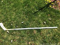 Full-length view of white wooden stick on grass, showing printed Toronto Maple Leafs lettering and logo