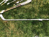 Full view of the white CCM hockey stick lying on grass, showing overall stick length and branding.