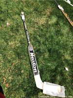 Full view of the Heston wooden hockey stick lying on grass showing the full stick length with branded blade and shaft.