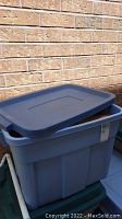 Blue plastic storage bin with lid, open and partially visible.