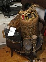 Overview showing the faux leather handbag, tall woven basket with braided straw, and other baskets arranged on a wooden chair.