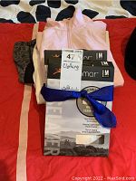 Photo of the clothing lot showing the Thermasilk long underwear packaging, light pink zip sweatshirts, and other clothing items neatly stacked.
