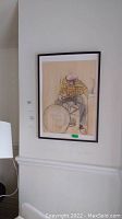 Framed drawing hanging on wall, showing man seated on stool.