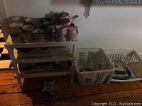 Wide view of multiple pottery items including mugs, teapot, creamer, sugar bowl, trays, and bowls arranged on shelves and baskets.