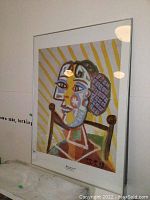 Full view of framed Picasso print leaning against wall, white mat and silver frame visible