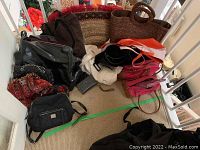 Various purses, tote bags, and wallets collected on a stair with different colors and sizes, mostly worn condition.
