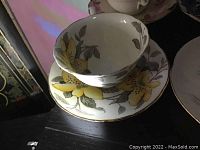 Teacup and saucer with yellow flower and gray leaves design, handle broken