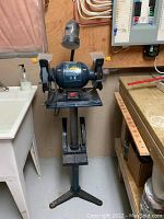 Full view of Mastercraft 6 inch bench grinder mounted on a metal stand, showing overall height and setup in workshop area.