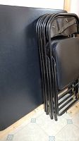 Side view of black metal folding chairs stacked together