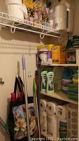 Photo of cleaning tools including mop, Swiffer, cleaning sprays, and paper products on shelves