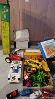 Overall lot including case, box of construction vehicles, semi-truck, helicopter box and book
