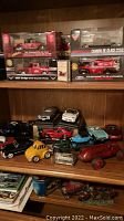 Model cars displayed on wooden shelf: boxed and loose models including Dodge Viper, Chevy Corvette, vintage cars