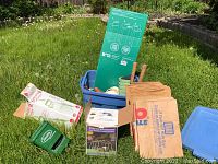 Overview photo of lot showing yard waste paper bags, gardening pots in blue tote, and gardening tool boxes on grass.
