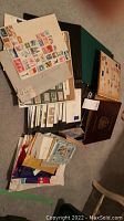 Overview of multiple stamp albums stacked with loose stamps on papers and envelopes spread around them.