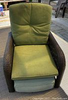 Front view of La-Z-Boy outdoor wicker recliner with green cushions on an outdoor deck.
