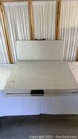 One plastic folding table in closed position showing carry handle, white plastic top with stains and marks.