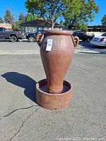 Front view of jug fountain standing on pavement showing jug and basin