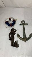 View of all three nautical wall decorations displayed on a white surface: lifesaver ring, mermaid figurine, and anchor