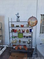 Full view of metal rack displaying garden pots, resin figures, and clock