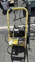 Full front view of Karcher pressure washer showing yellow frame, engine, control panel, and attached hose and gun