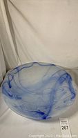 Top down view of large round frosted glass bowl with blue swirl patterns on white frosted base.