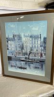 Framed art print showing canal and buildings scene with boats and reflections in water.