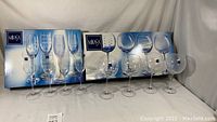 Full set of Mikasa glassware with original boxes showing four balloon goblets and four fluted champagne glasses on display.