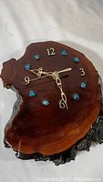 Full view of wood slab wall clock with turquoise stone hour markers and gold-tone hands.