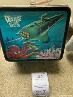 Front view of the vintage lunchbox showing submarine and octopus artwork and title text. Some wear and rust visible.