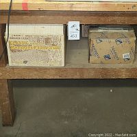 Three boxes on a wooden shelf, two boxes labeled 'Classic Solid Oak Parquet Floor Tile' and one box labeled 'Newbridge' thin bricks.
